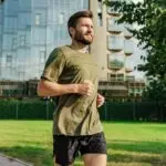 Man in sportswear jogging through the city park, focusing on his workout routine.