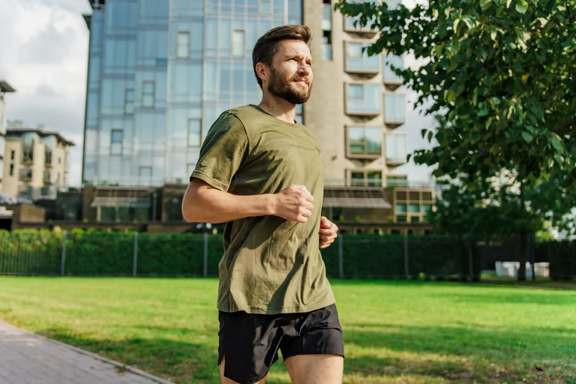 Man in sportswear jogging through the city park, focusing on his workout routine.